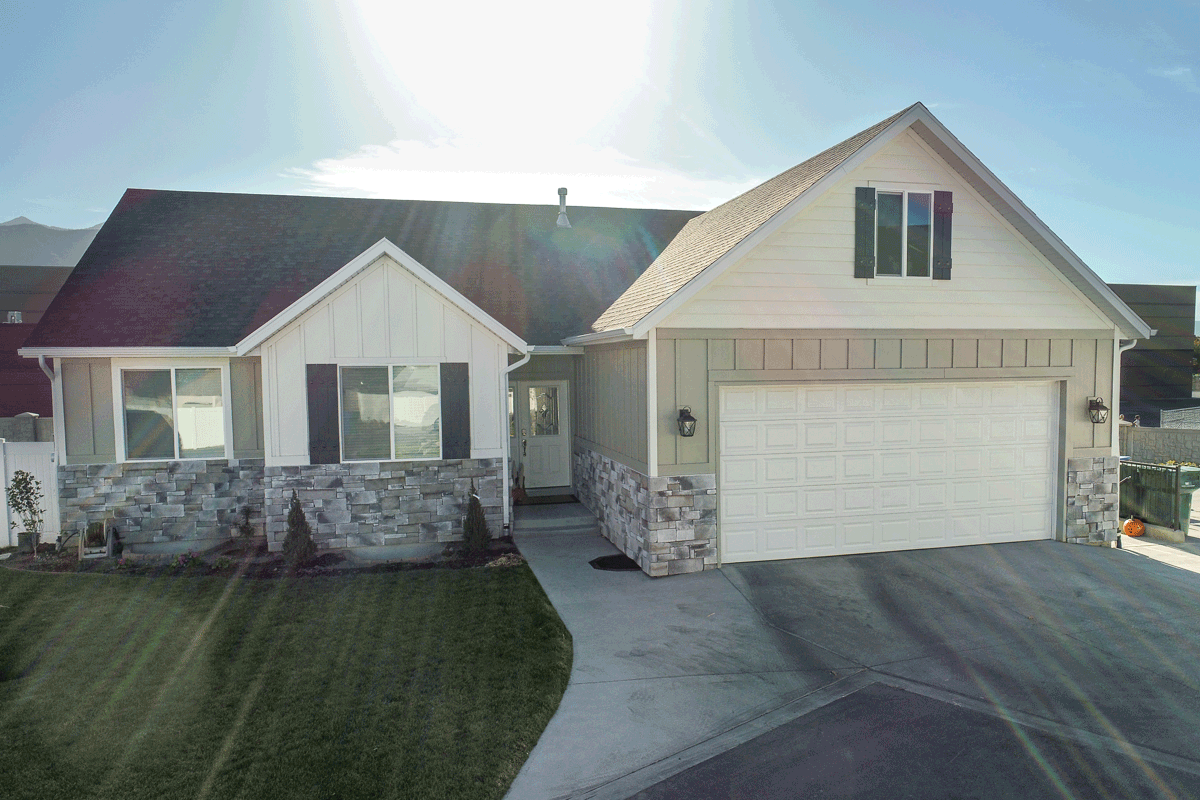 House plan exterior showing a Modern Farmhouse style with a two-car garage, gabled dormer, and stone skirting.