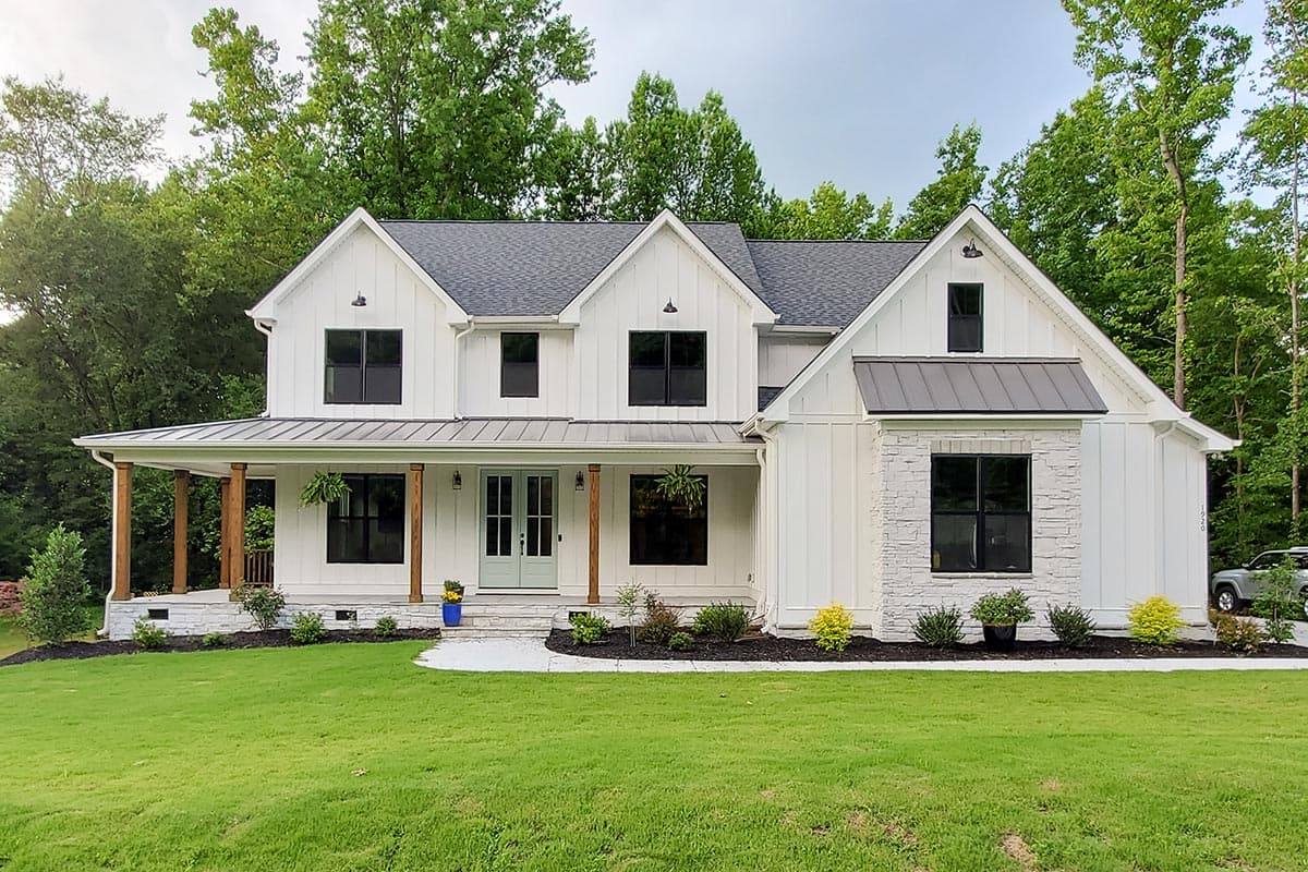 Modern Farmhouse house plan exterior. Two-story home with porch, gables, and board-and-batten siding. Features stone accent and dark-trimmed windows.