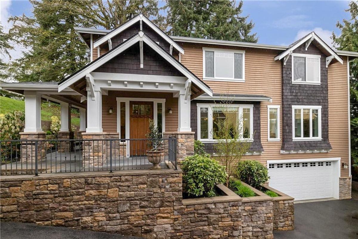 House plan exterior. Craftsman-style home with two stories. Features include a front porch, multiple gables, and a stone facade on the lower level.