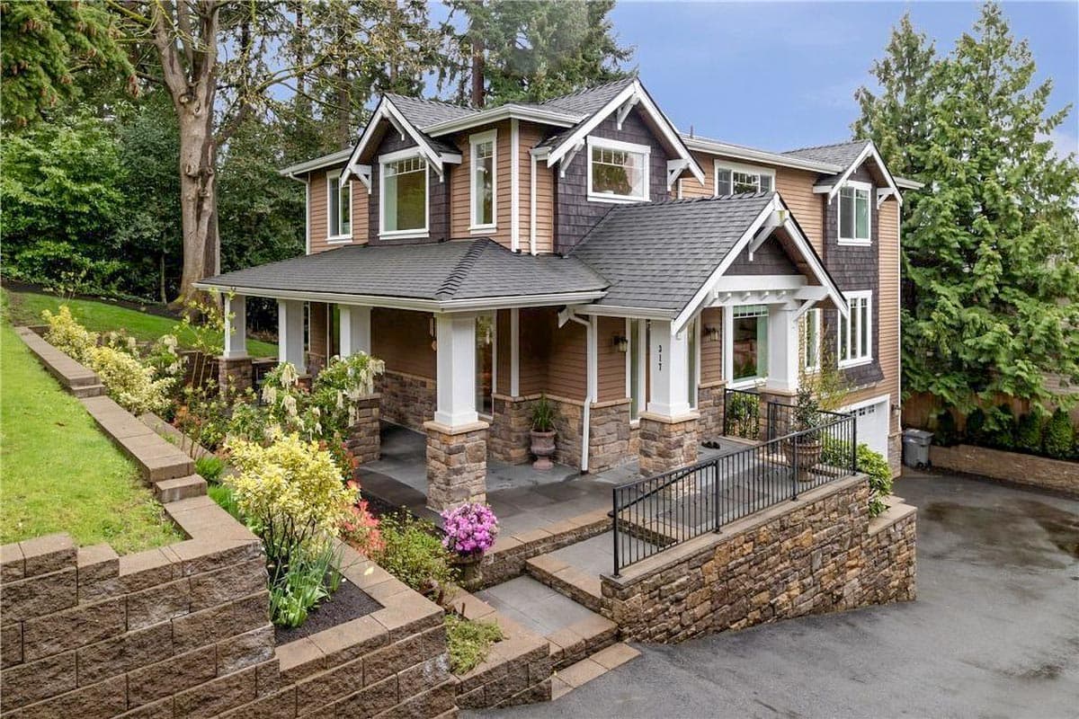 House plan exterior: Two-story home with wrap-around porch, stone accents, multiple gables, and dormer windows.