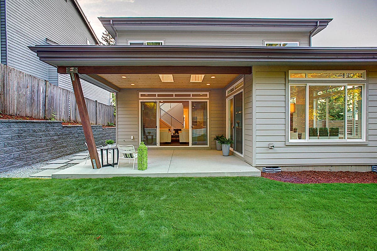 Modern house exterior with covered patio, large windows, and sloped rooflines.
