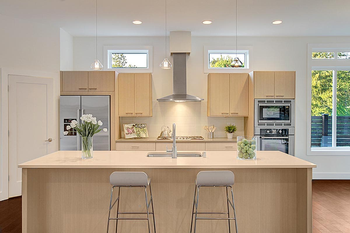 Kitchen featuring a large island with seating, stainless steel appliances, and natural wood cabinetry.