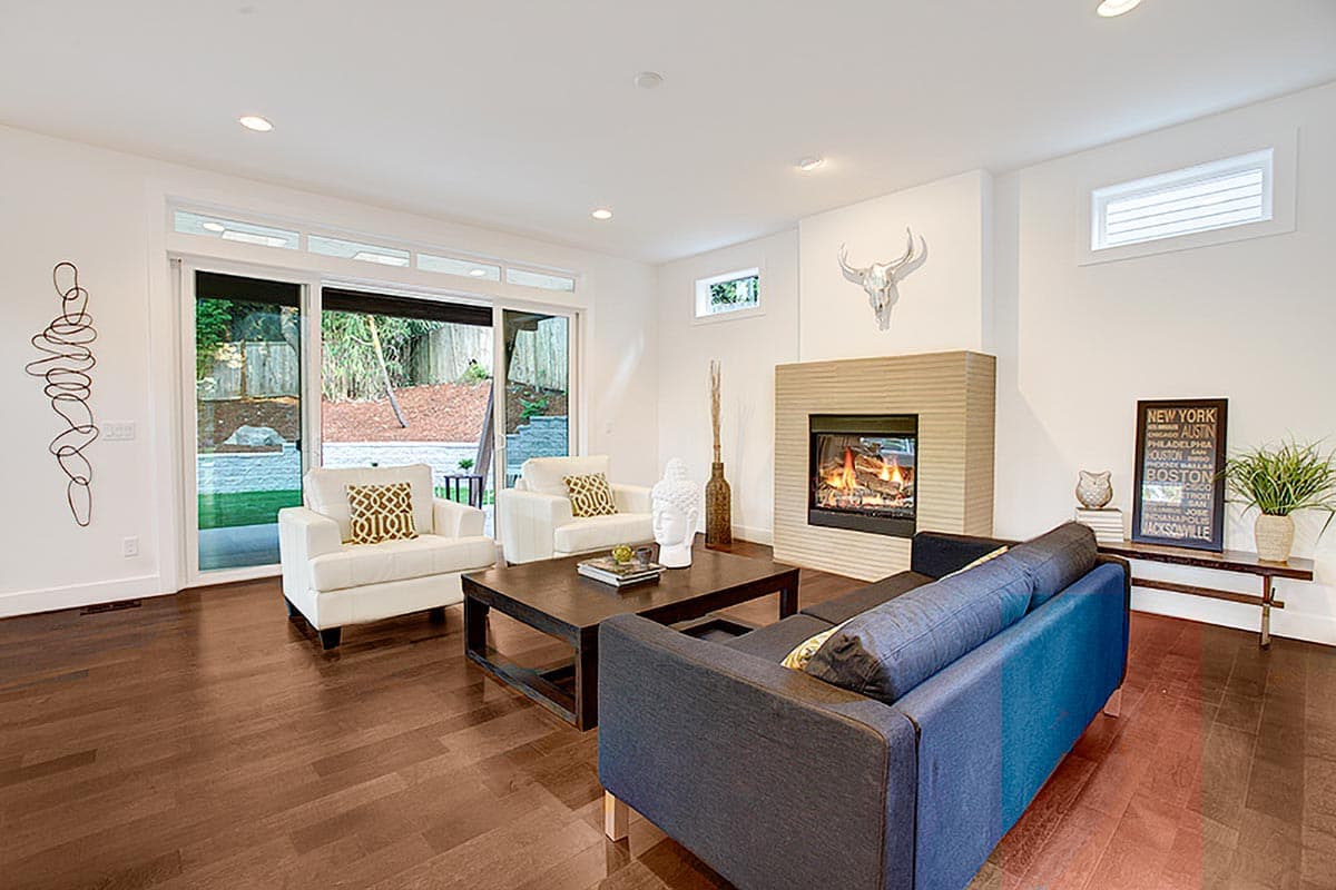 Living room with fireplace, modern furniture, and sliding glass doors opening to a backyard.