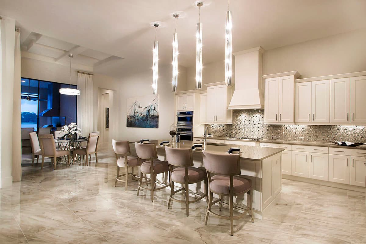 Open-concept kitchen and dining area with large island, white cabinets, mosaic tile backsplash, and pendant lighting.