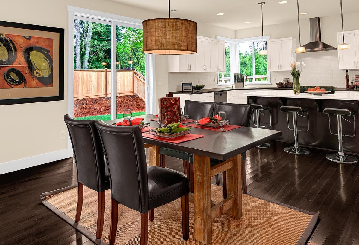 Dining area and kitchen with island, white cabinetry, stainless steel appliances, and sliding glass doors to backyard.