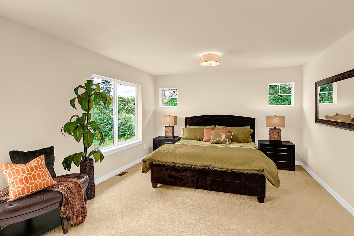 Bedroom with queen bed, two nightstands, large window, and a seating bench with decorative pillows and throw blanket.