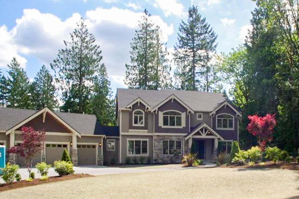 House plan exterior: Two-story home with attached two-car garage, prominent gables, stone accents, and covered entry.