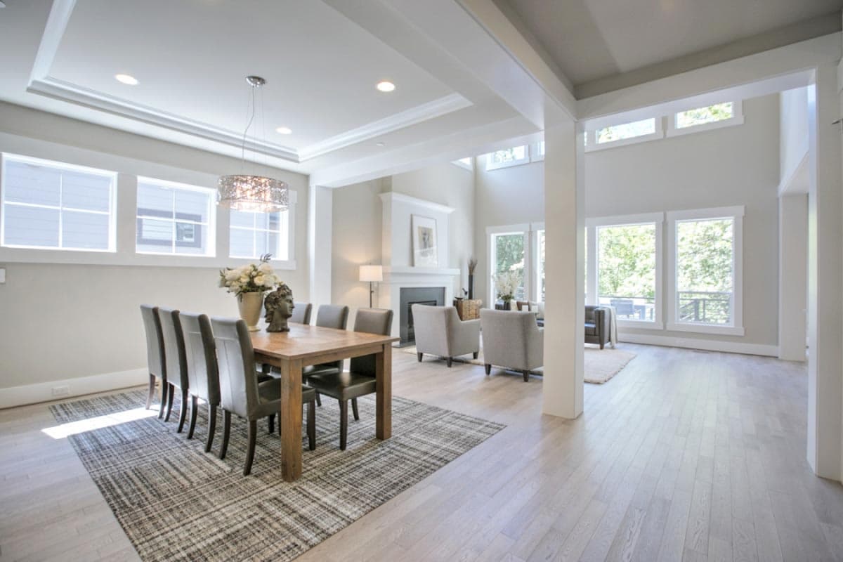 Dining area with rectangular wood table and chairs, open to living area with fireplace and large windows.