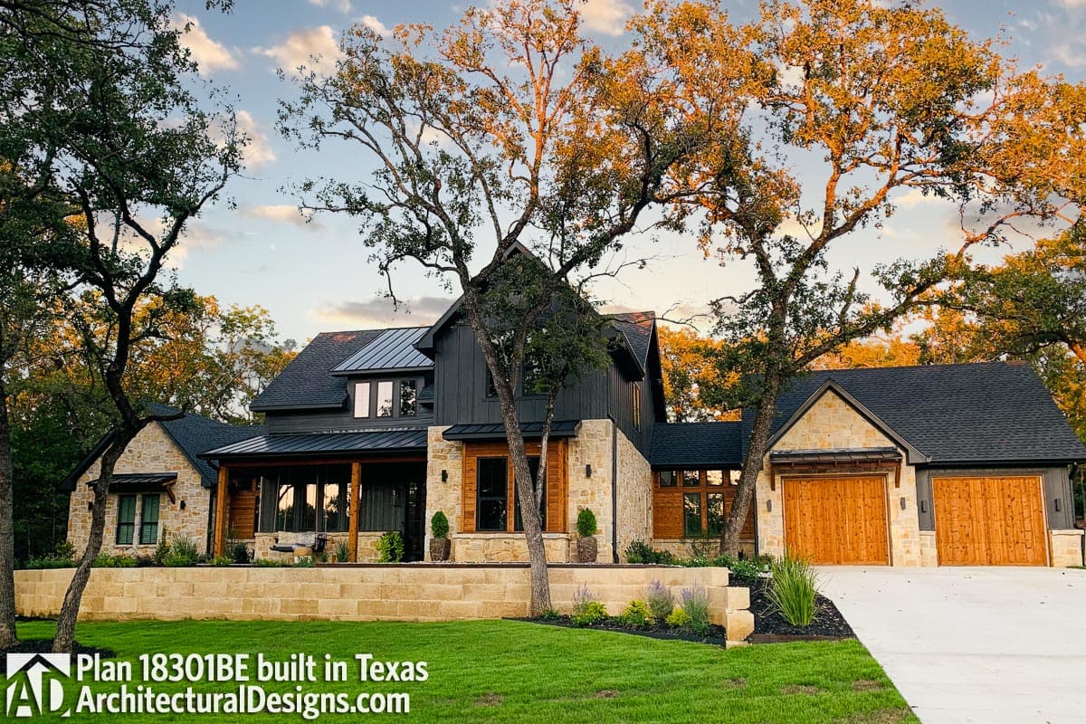 Modern Farmhouse house plan exterior, two stories, metal roof, stone and wood siding, covered porch, and a three-car garage.
