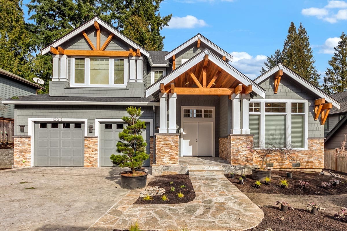 House plan exterior view of a two-story Craftsman home with a front porch, gables, exposed rafter tails, and a two-car garage.