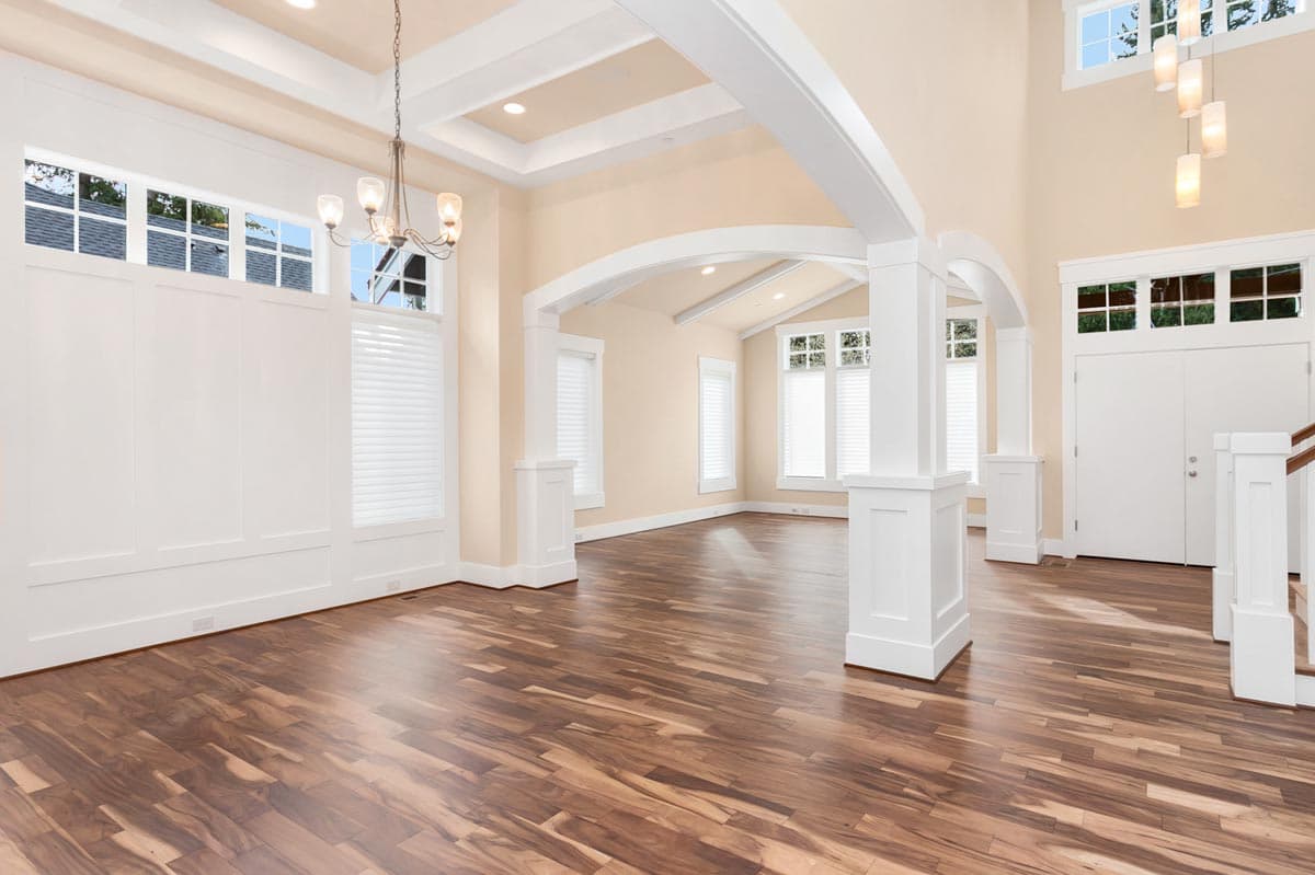 Interior rendering of a great room with coffered ceiling, arched doorways, decorative beams, and a two-story entryway.