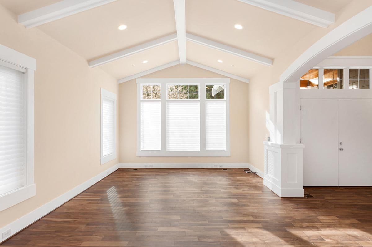 Interior rendering of a room with vaulted ceiling, exposed beams, large bay window, and double doors.