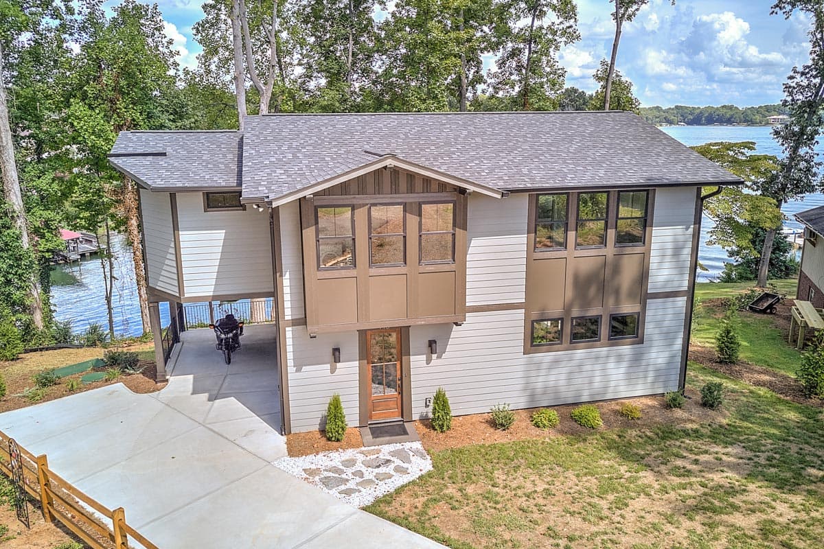 House plan exterior: Modern style, two-story, with a covered carport, prominent gables, and multi-pane windows.