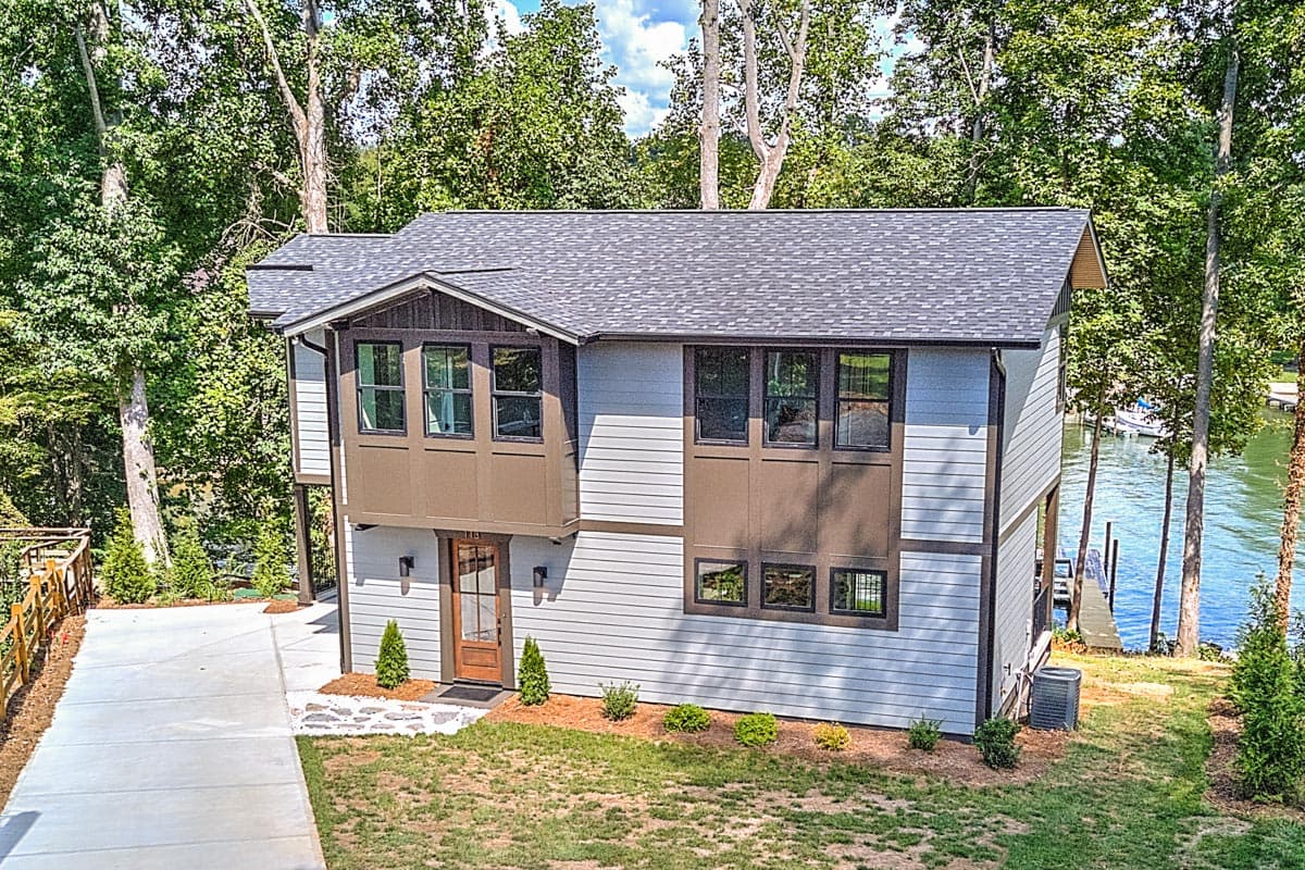 Two-story house plan exterior with lap siding, multiple gables, a bay window, and a lakeside setting.