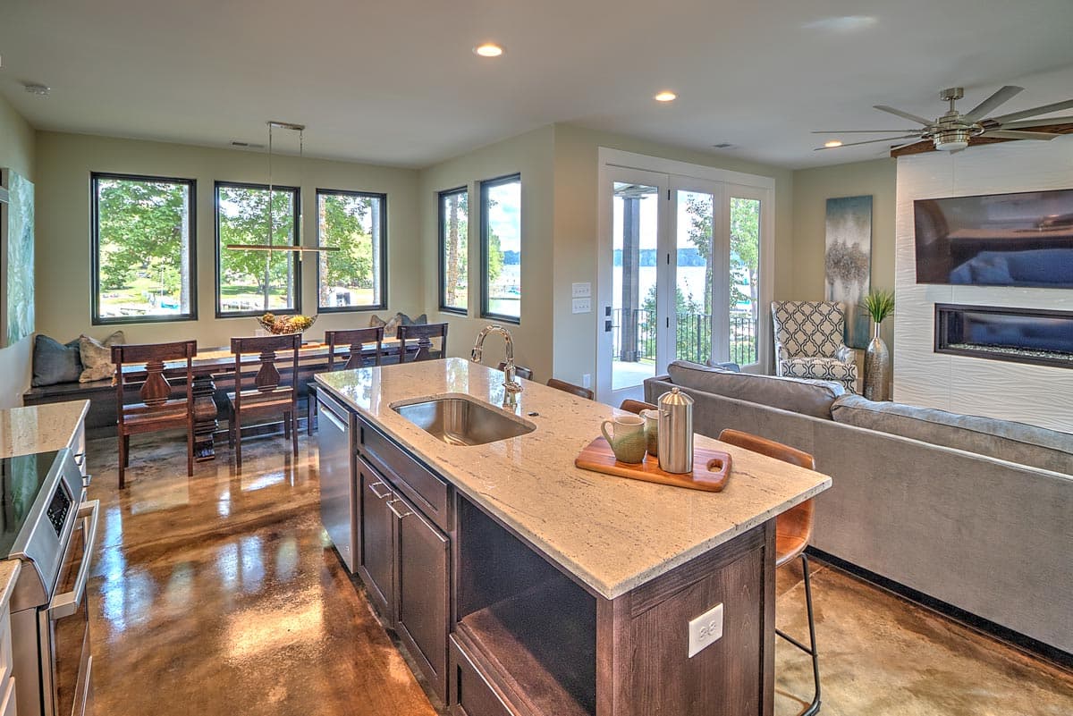 Modern open-concept living space with kitchen island, dining area, and living room featuring a fireplace.