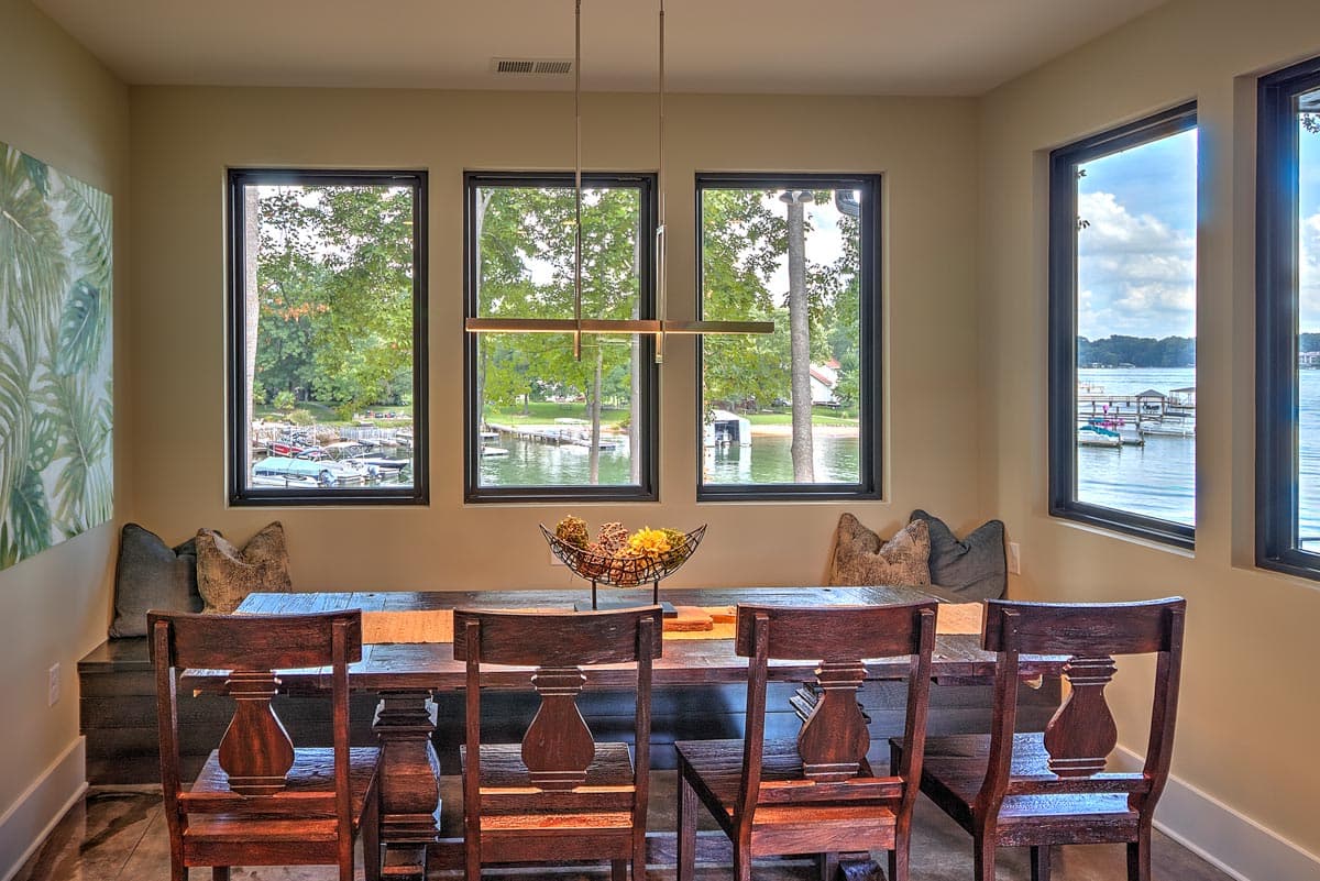 Dining room with lake view, large windows, and wooden table and chairs.