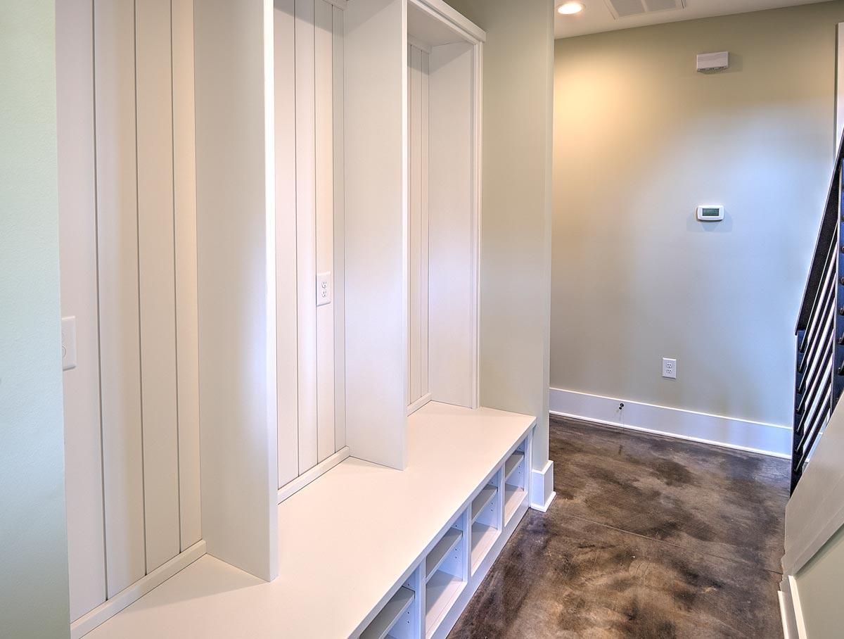 Mudroom entryway with built-in white cubbies, bench seating, and vertical wood paneling.