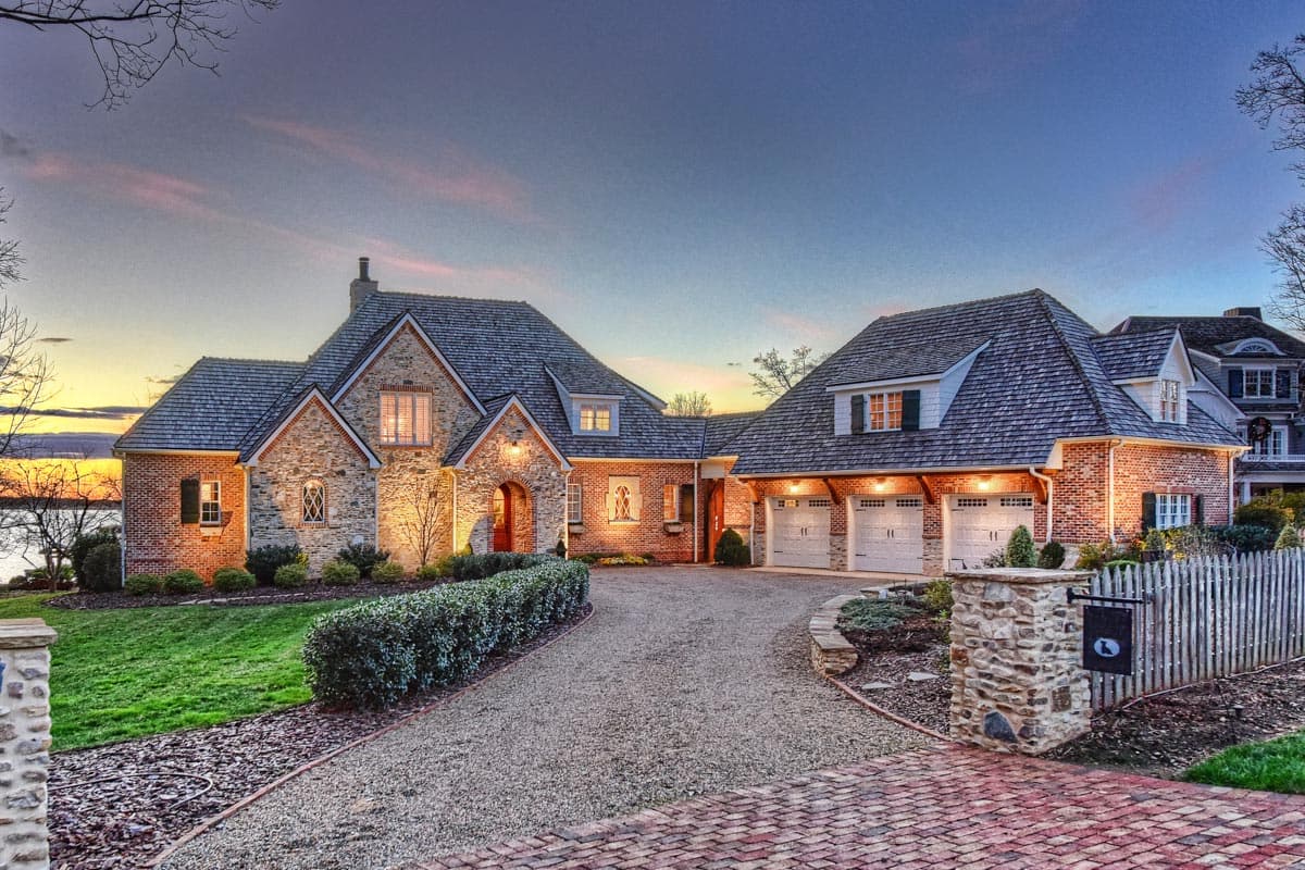 House plan exterior featuring stone and brick facade, multiple gables, arched entryway, and a three-car garage.