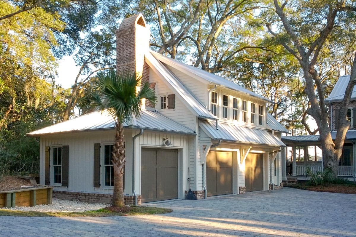 House plan exterior: Coastal style two-story home with metal roof, large brick chimney, and three-car garage.