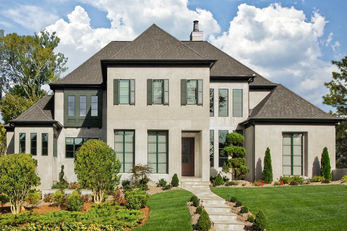 House plan exterior, two stories, stucco facade, gabled roof, multiple window styles including bay and tall vertical.