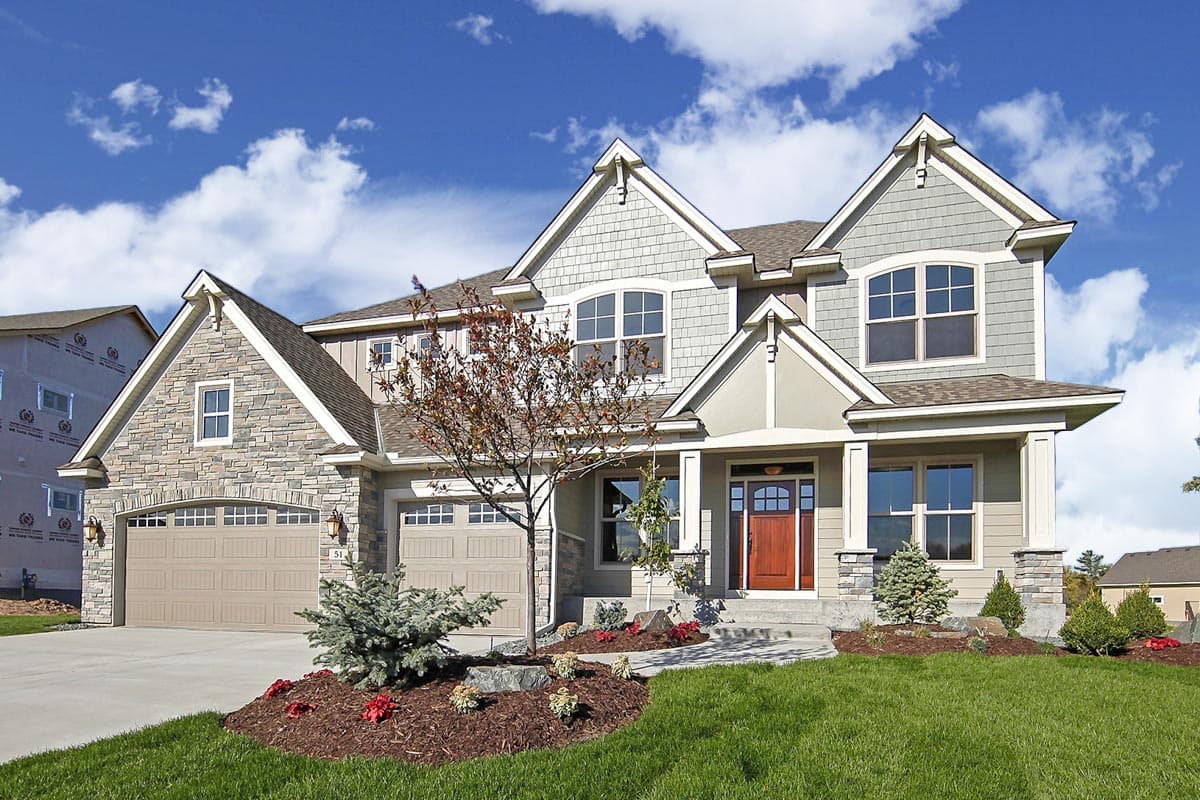 House plan exterior. Two-story with Craftsman details: gabled rooflines, stone and shake siding, and a front porch. Features an attached garage.