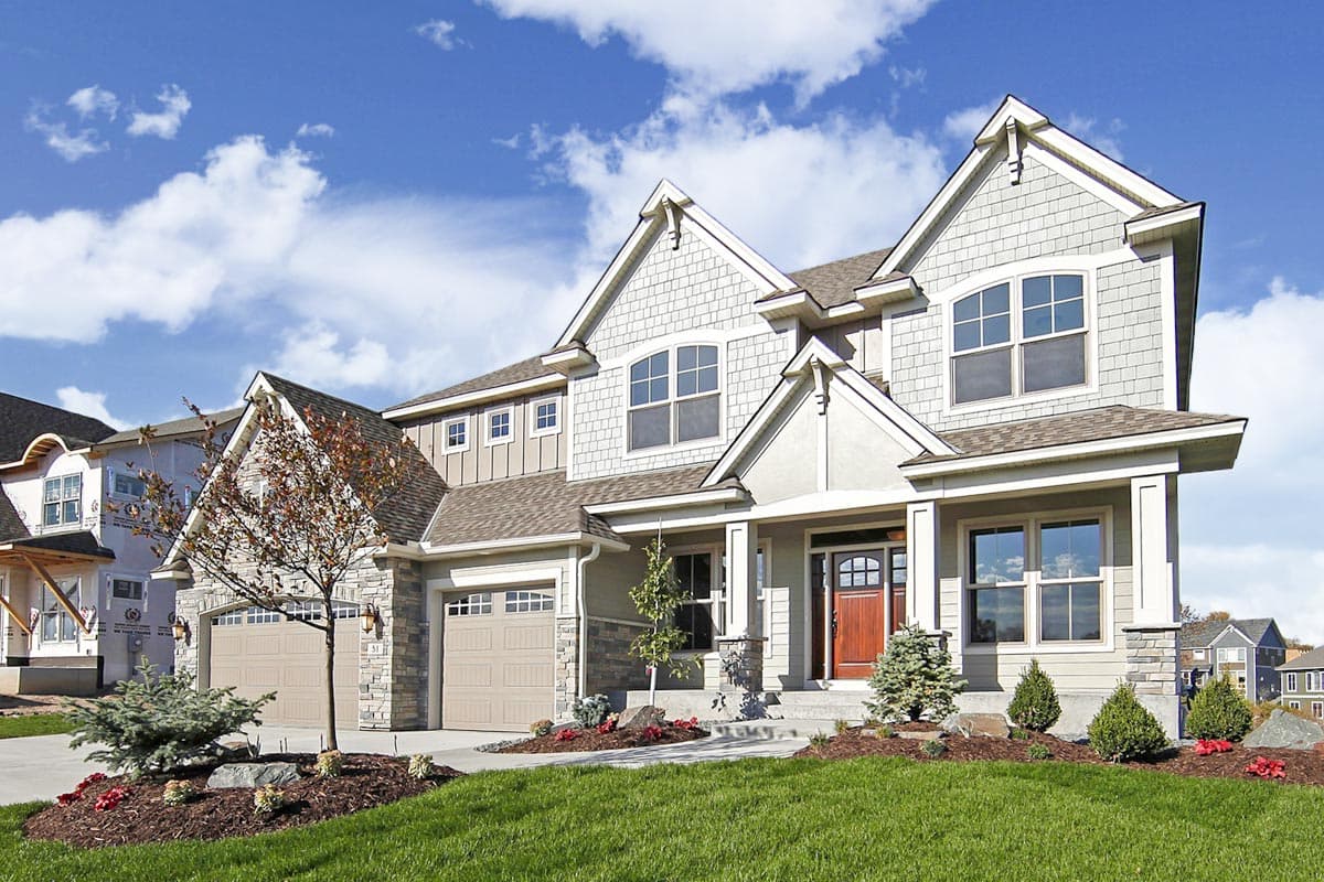 House plan exterior: Two-story home with stone accents, dual gables, covered entry, and a three-car garage.