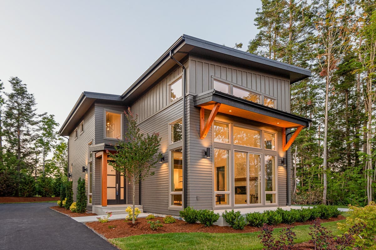 House plan exterior with modern design. Two-story home with large windows, angled rooflines, and exposed wood bracket supports.