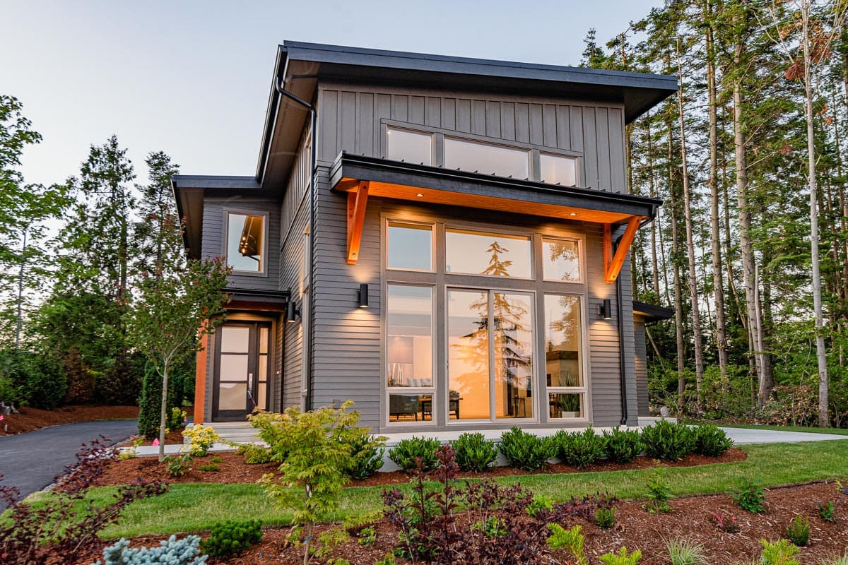 Modern house plan exterior with multiple gables, large windows, wood accents, and a flat roof.