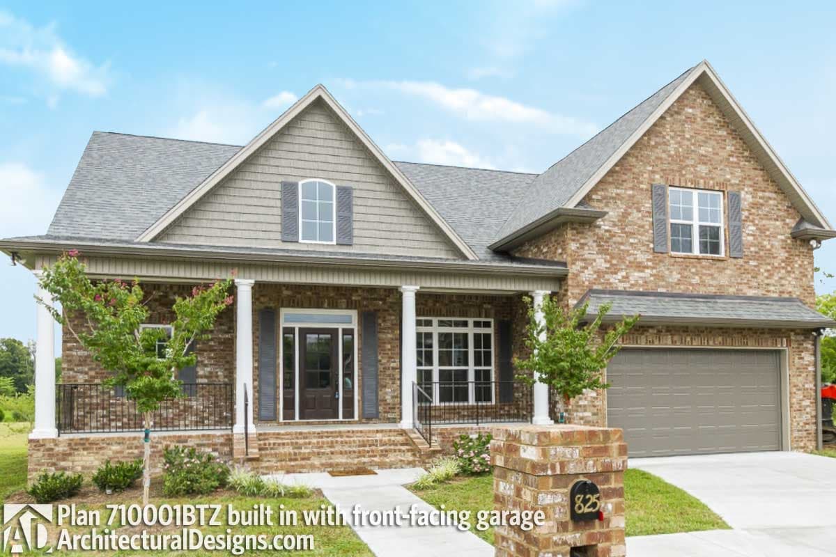 House plan exterior: two-story brick home with a covered front porch, arched dormer window, and front-facing garage.
