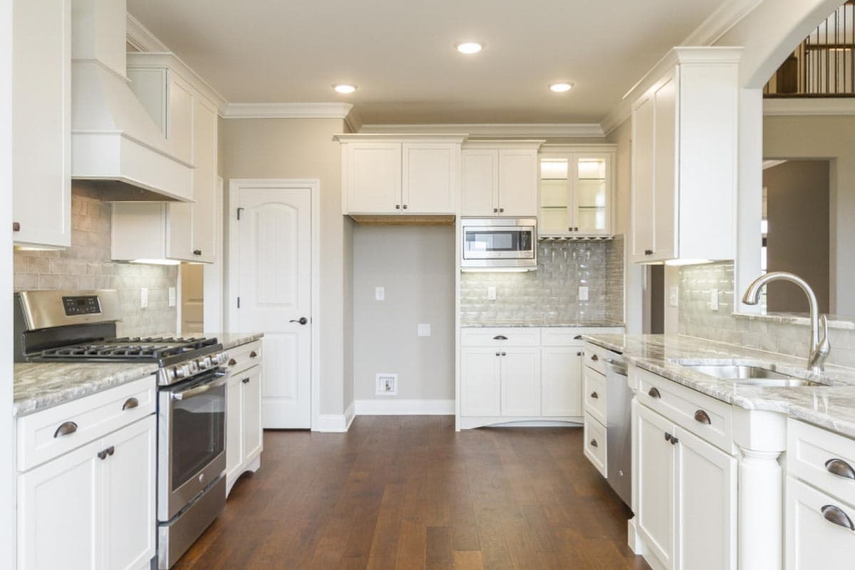 Kitchen with white cabinetry, stainless steel appliances, granite countertops, and dark hardwood flooring.