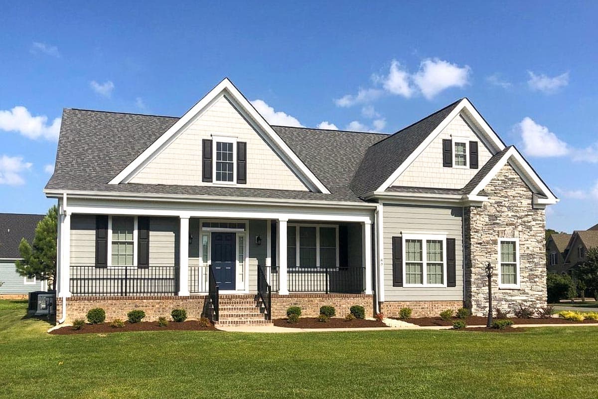 House plan exterior. Two-story with front porch, gable roof, and stone facade on a portion of the structure. Features black shutters.