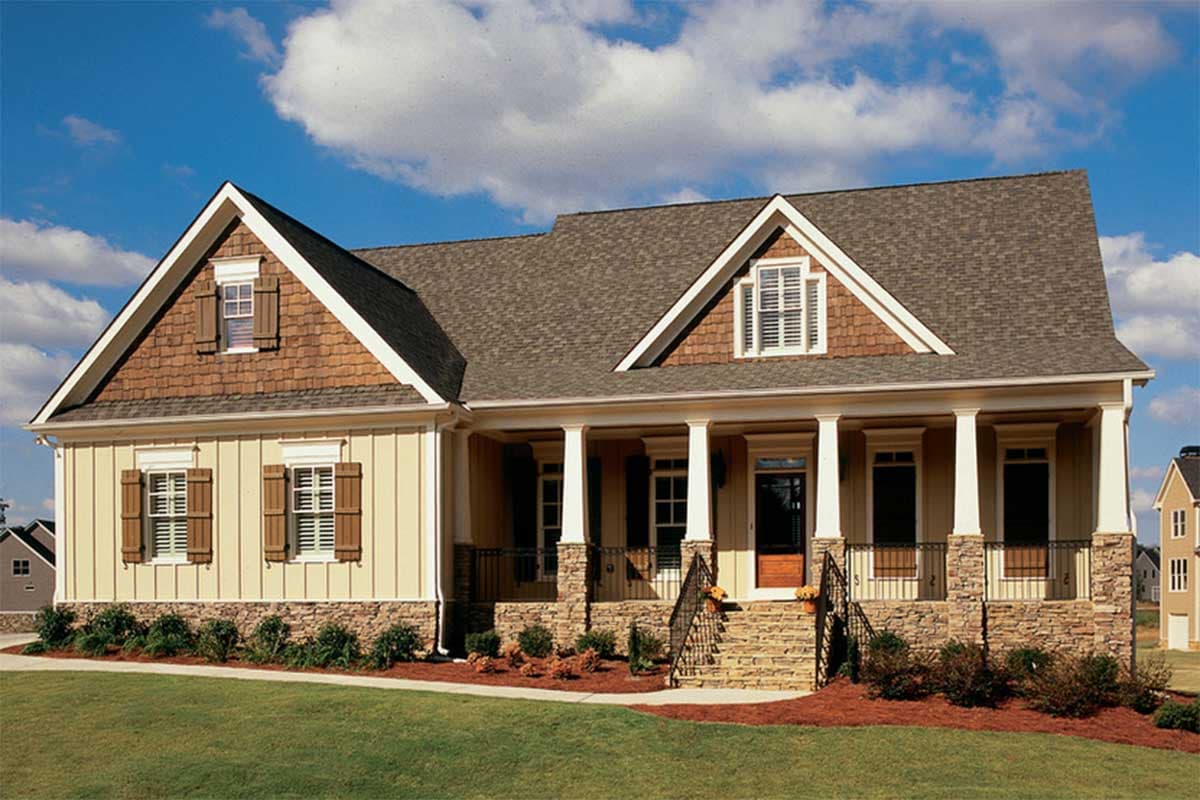 House plan exterior of a one-story home with a gabled dormer, shingle siding, stone accents, and a wrap-around porch with columns.