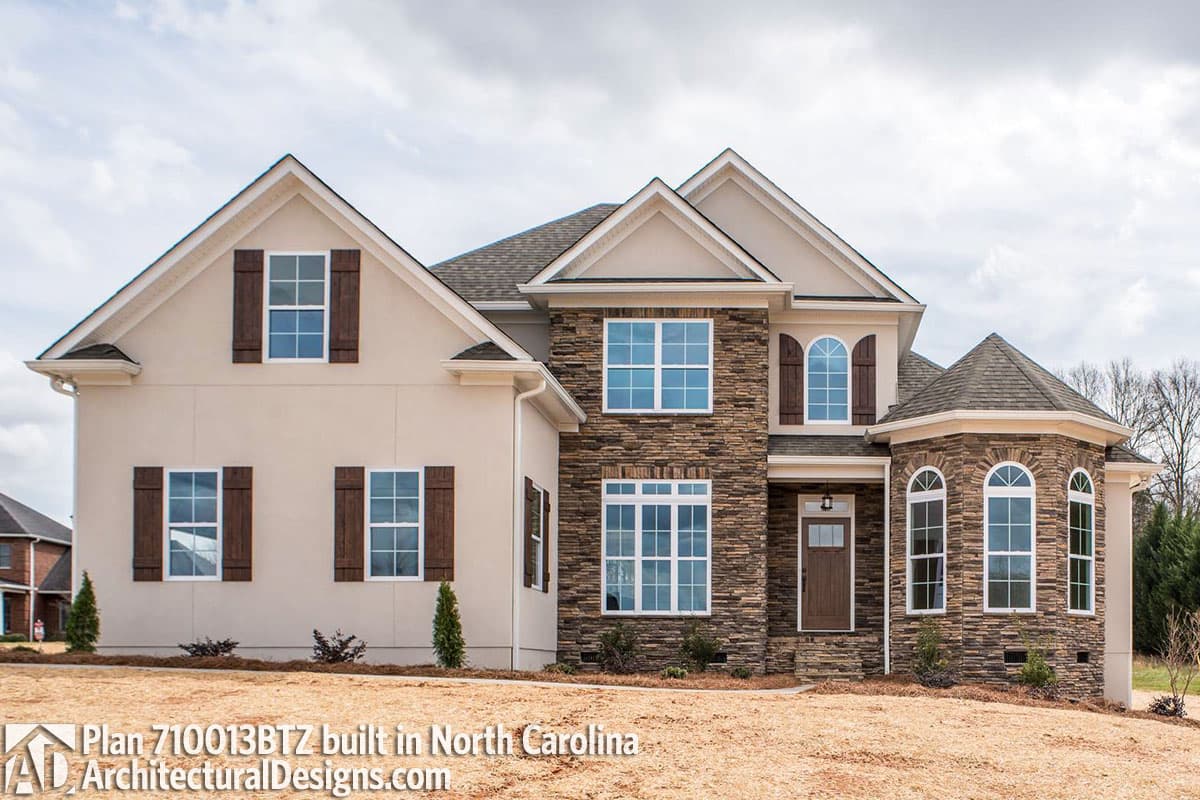 House plan exterior with stone facade, multiple gables, and arched entryway windows.