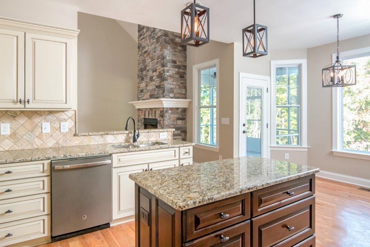 Kitchen featuring a stone fireplace, granite countertops, stainless steel dishwasher, and a dark wood island with granite top.