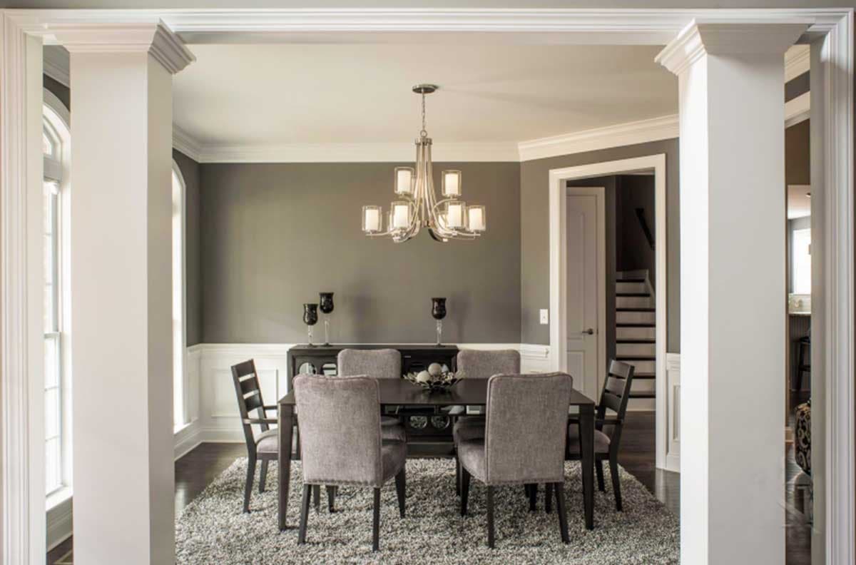 Dining room with table, upholstered chairs, sideboard, chandelier, and wainscoting.
