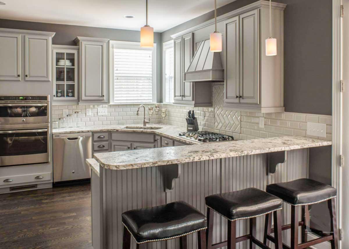 Kitchen with gray cabinets, granite countertops, stainless steel appliances, subway tile backsplash, and breakfast bar with seating.