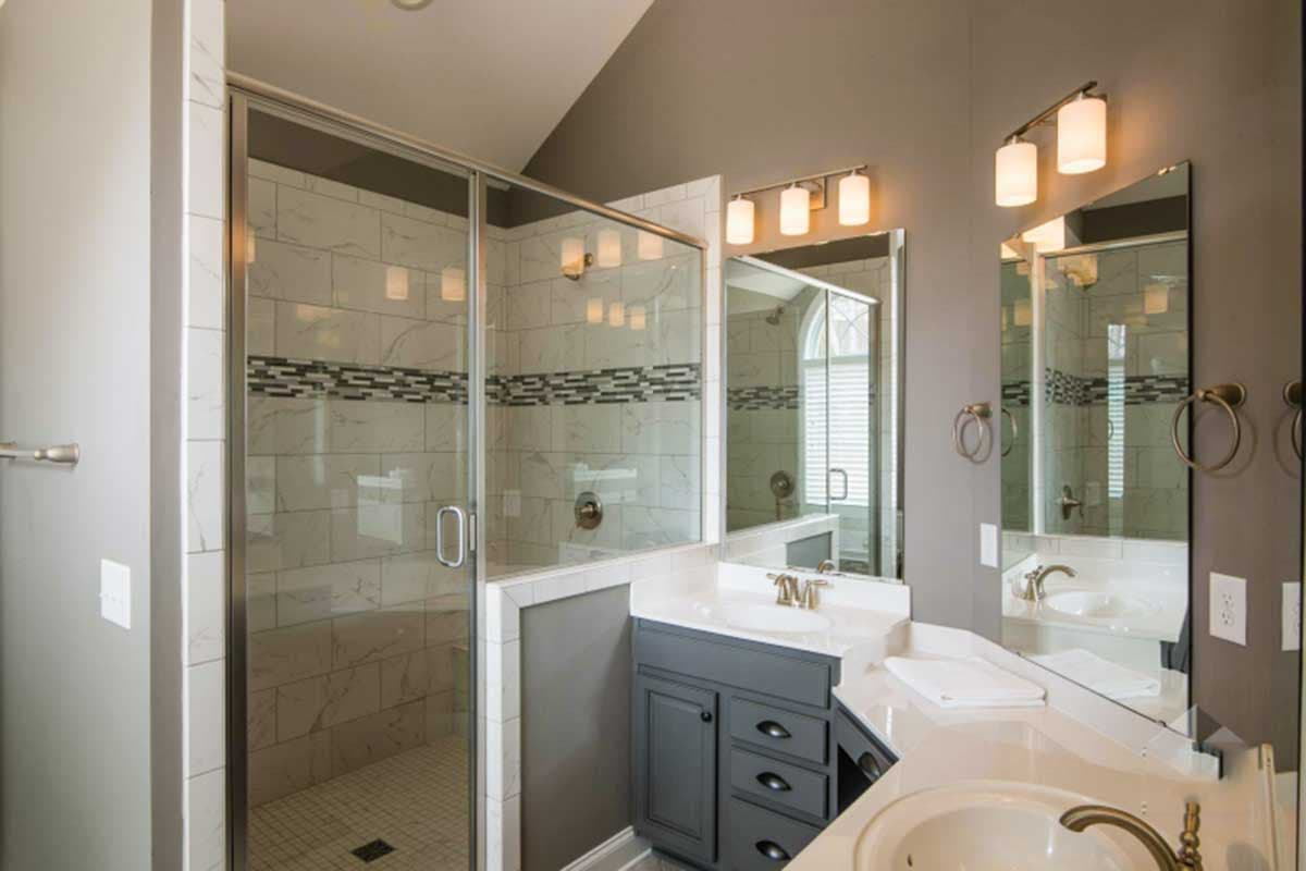 Master bathroom with glass-enclosed shower, double vanity with marble countertop, and dark gray cabinetry.