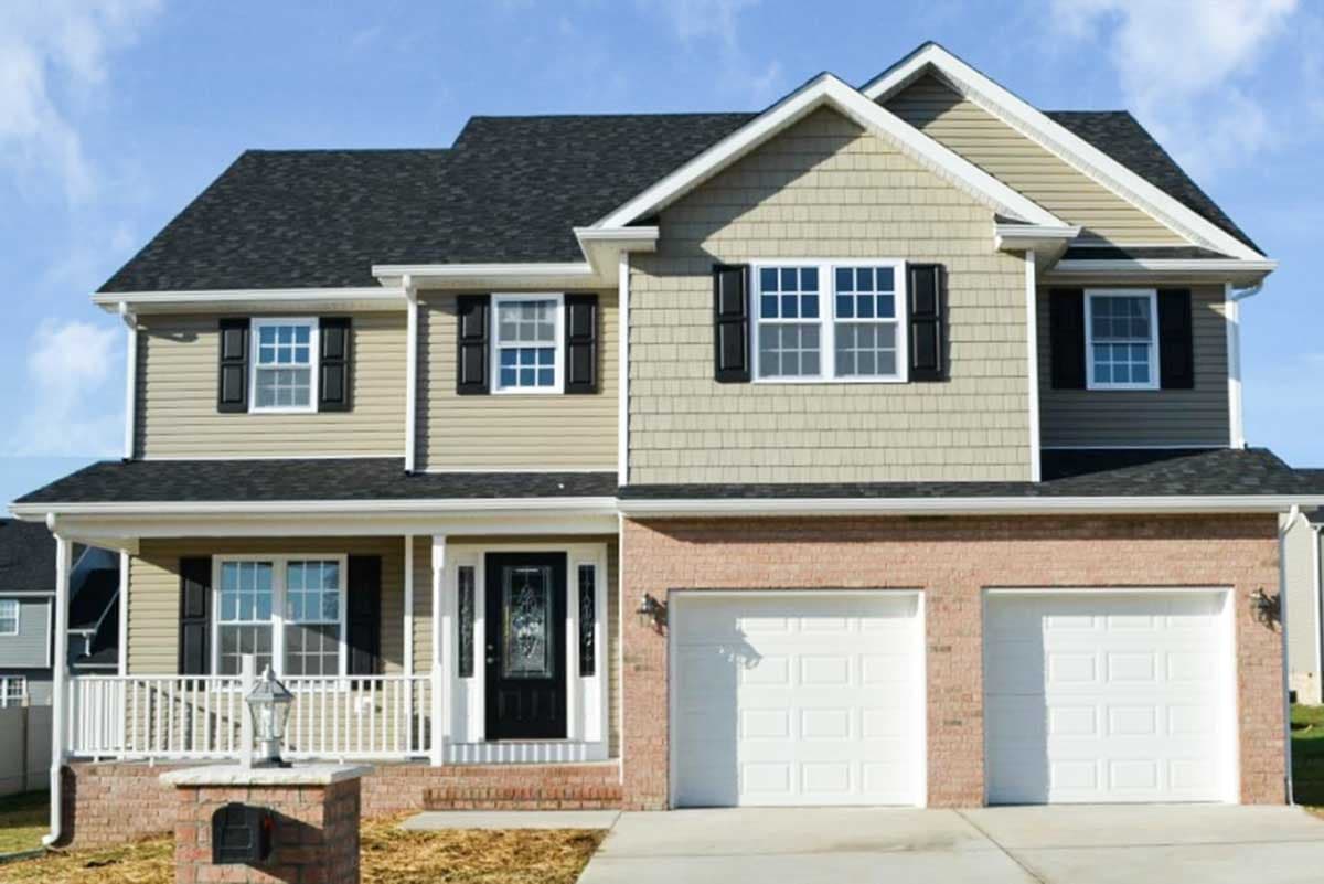 Two-story house plan exterior with a covered front porch, gable dormers, shingle siding, and a side-entry two-car garage.