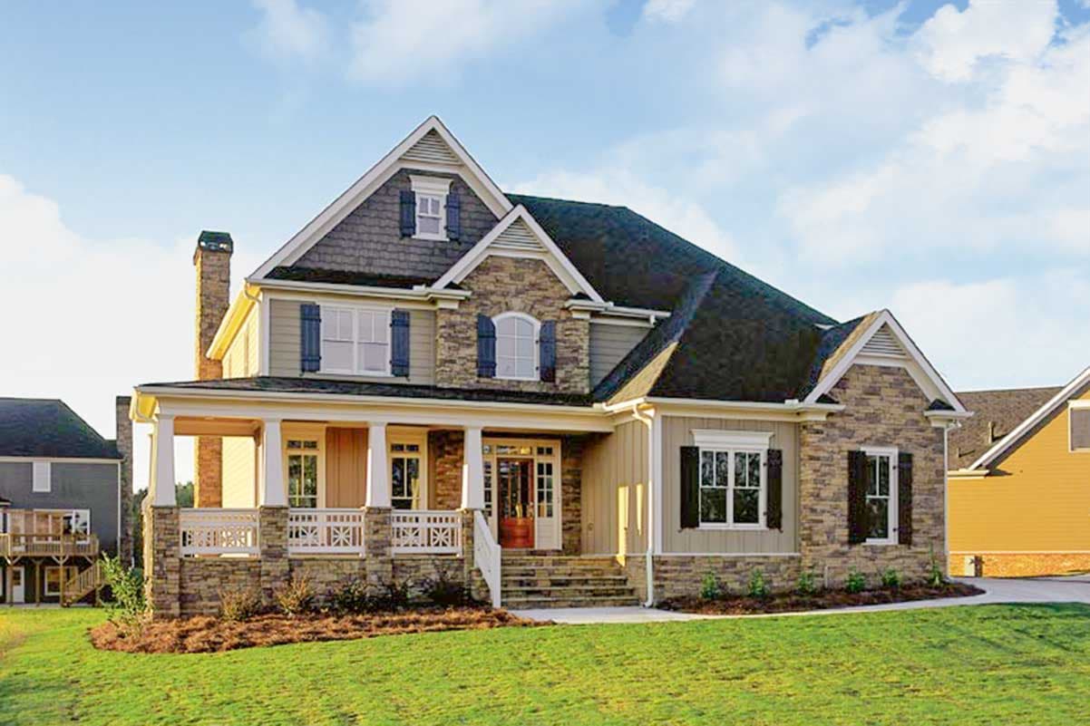 House plan exterior. Two-story home with a porch, gables, stone facade, and dormer. Features include a side-entry garage.