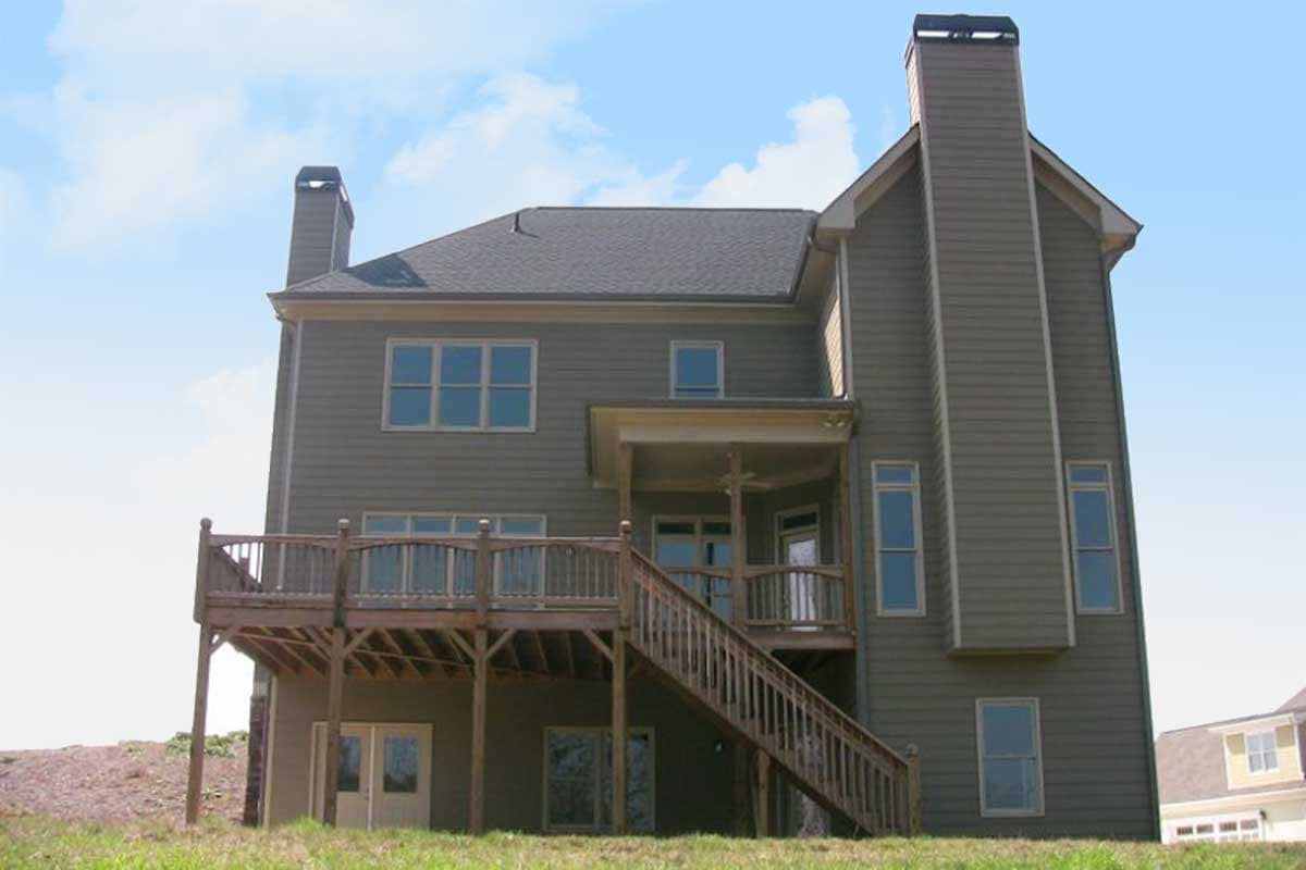 House plan exterior showing a two-story home with a large wooden deck, two chimneys, and a covered porch.