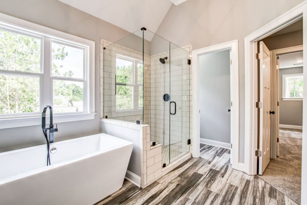 Bathroom with freestanding tub, glass-enclosed shower with subway tile, and wood-look plank flooring.
