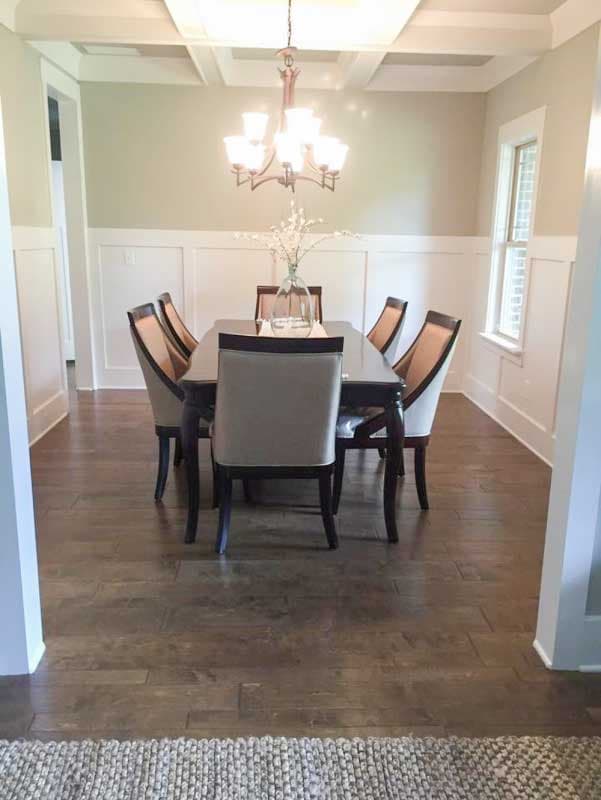 Dining room with coffered ceiling, wainscoting, rectangular table, and upholstered chairs.