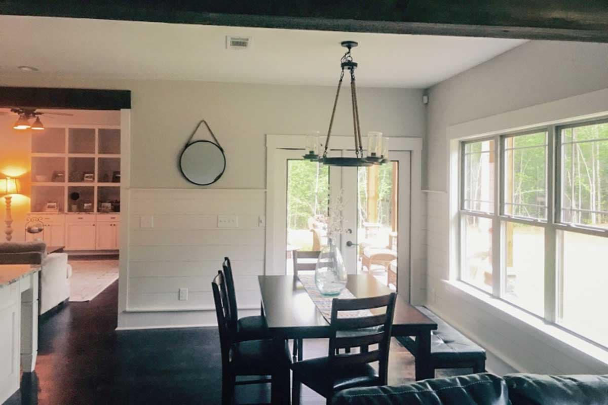 Dining area with table, chairs, bench, and double doors to patio. Adjacent living area with built-in shelving.