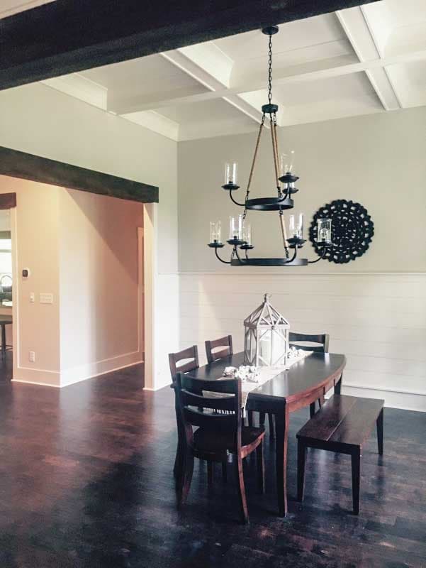 Dining room with coffered ceiling, dark wood table and chairs, and shiplap wall.