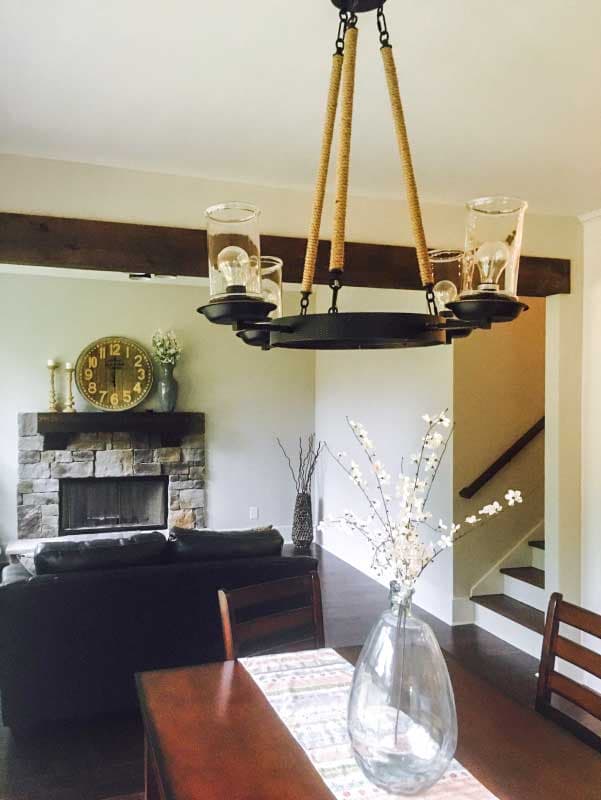 Interior view of living room with stone fireplace, wood beam ceiling, and farmhouse chandelier.