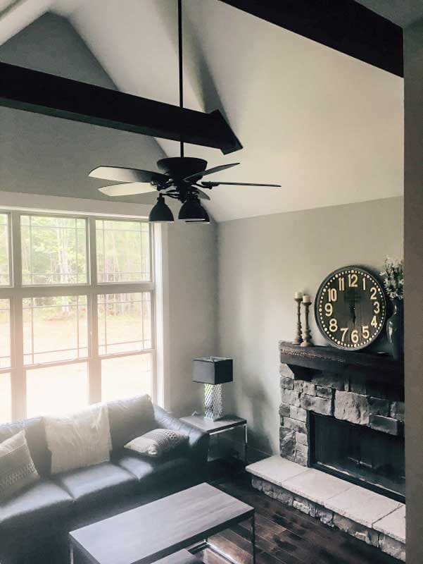 Interior view of great room with vaulted ceiling, exposed beams, stone fireplace, and large windows.