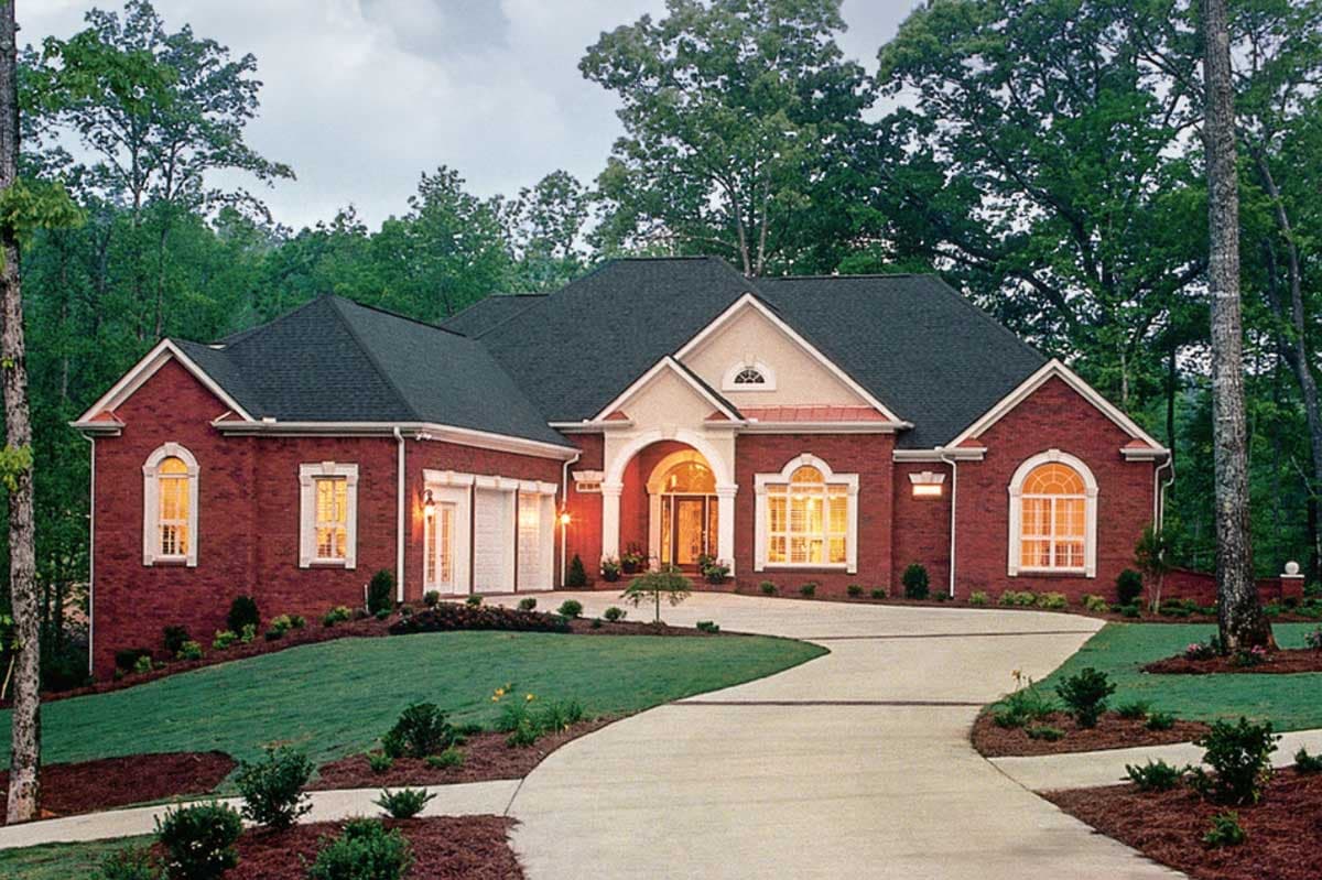 House plan exterior: Red brick, one-story home with arched entryway, side-facing garage, and multiple gables.