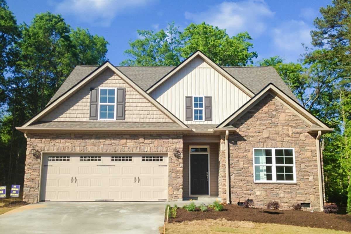 House plan exterior with stone veneer, gabled roof, and two-car garage. Features include shake siding and multiple gables with decorative shutters.