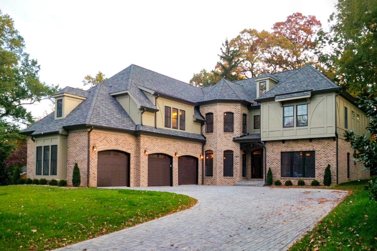 House plan exterior: Two-story brick home with multi-gabled roof, three-car garage, and turret.
