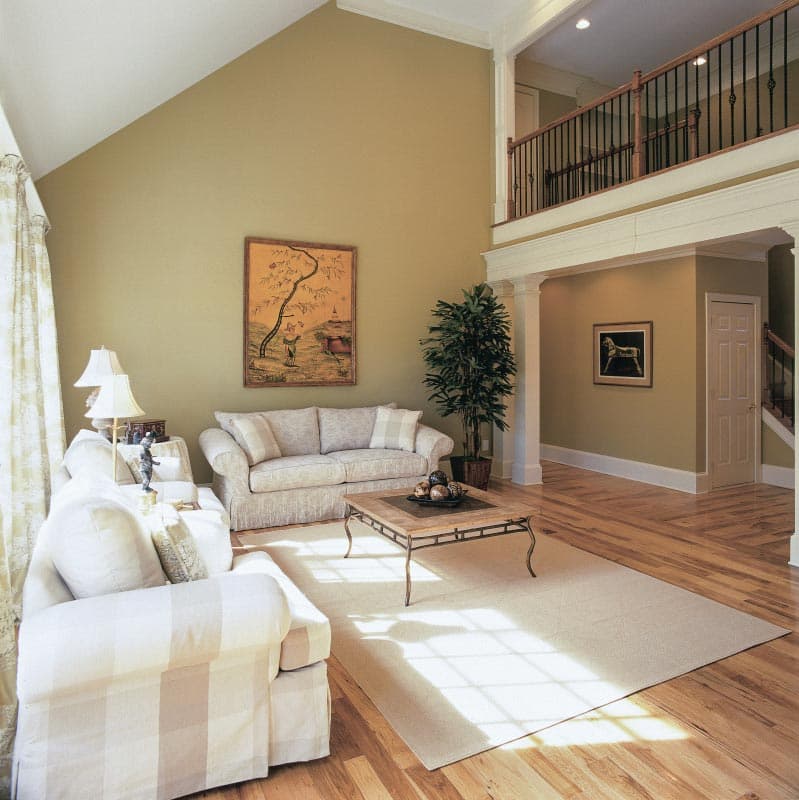 Great room with vaulted ceiling, balcony overlook, fireplace, and hardwood floors.